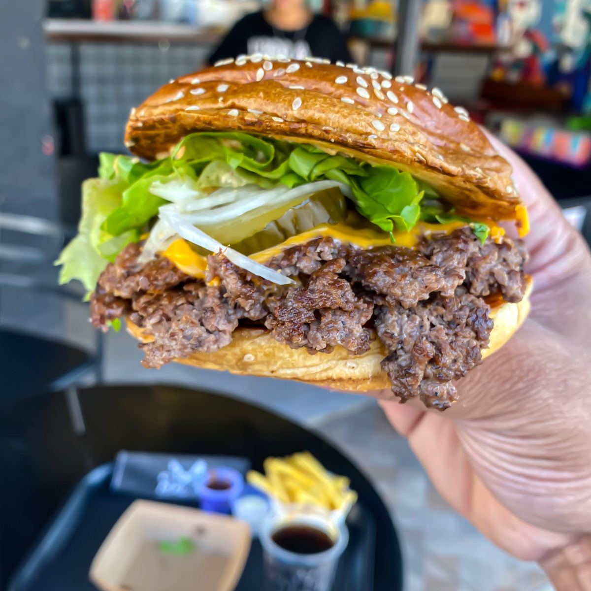 Big Smack da Malta Parrilla segurado em uma mão, com ambiente desfocado ao fundo